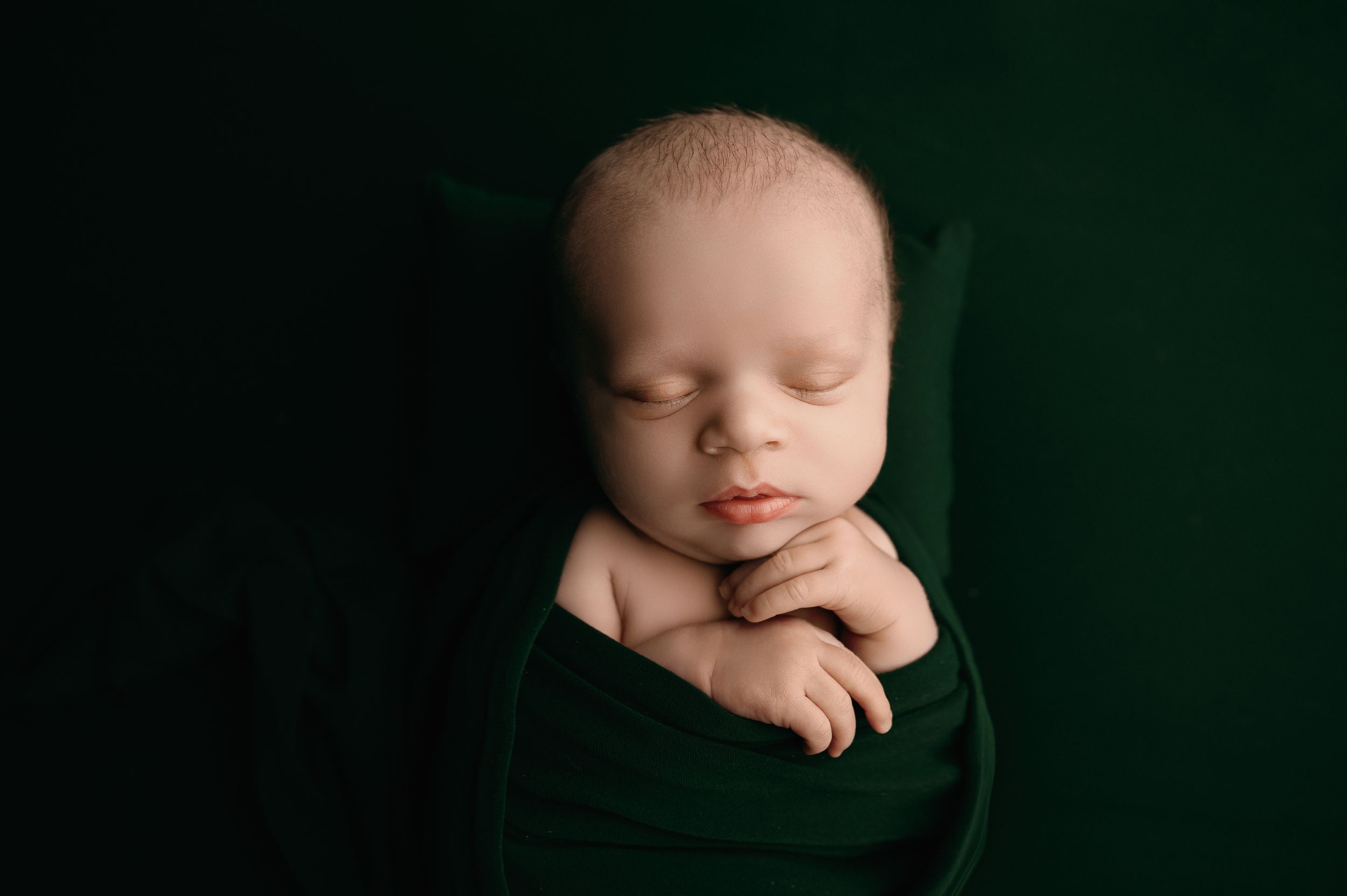 A series of artistic newborn baby portraits in dark moody lighting showing close-up details and poses.