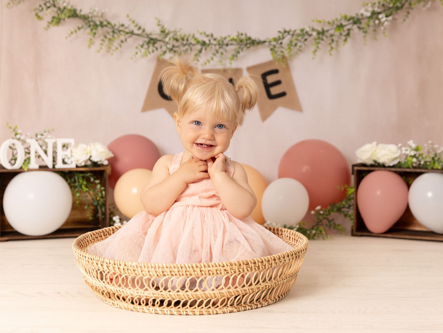 A baby in a green gingham outfit plays with colorful sprinkles during a cake smash photo session.