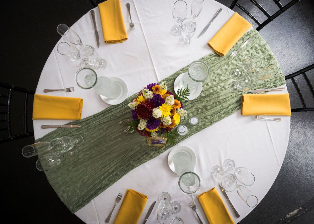 Overhead view of a round table setting with yellow napkins and white plates arranged in a circular pattern.