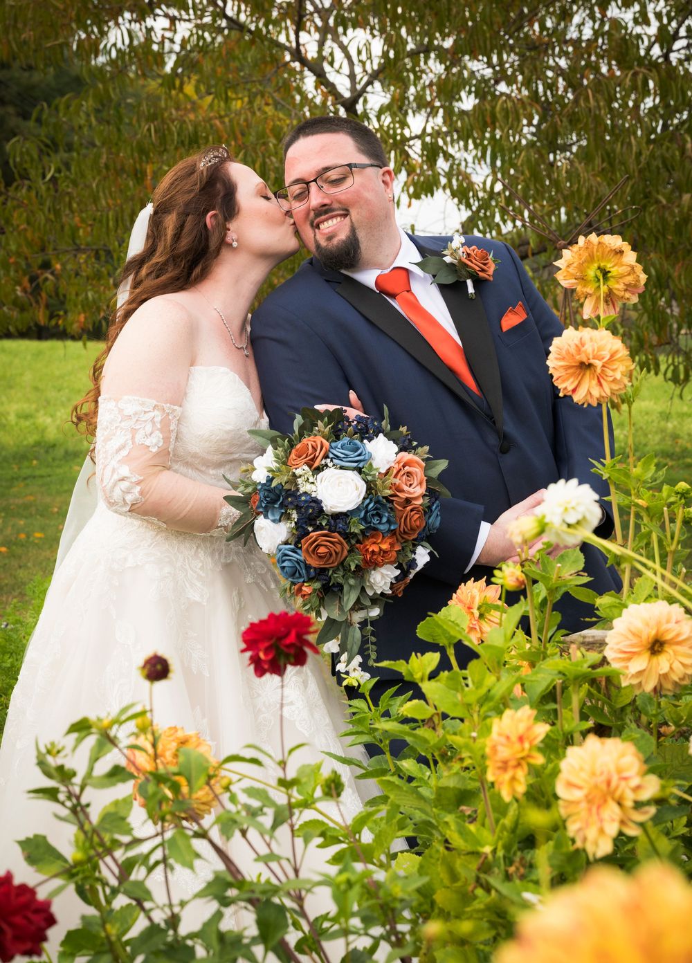 Romantic garden wedding scene with orange dahlias and floral arrangements in the foreground.