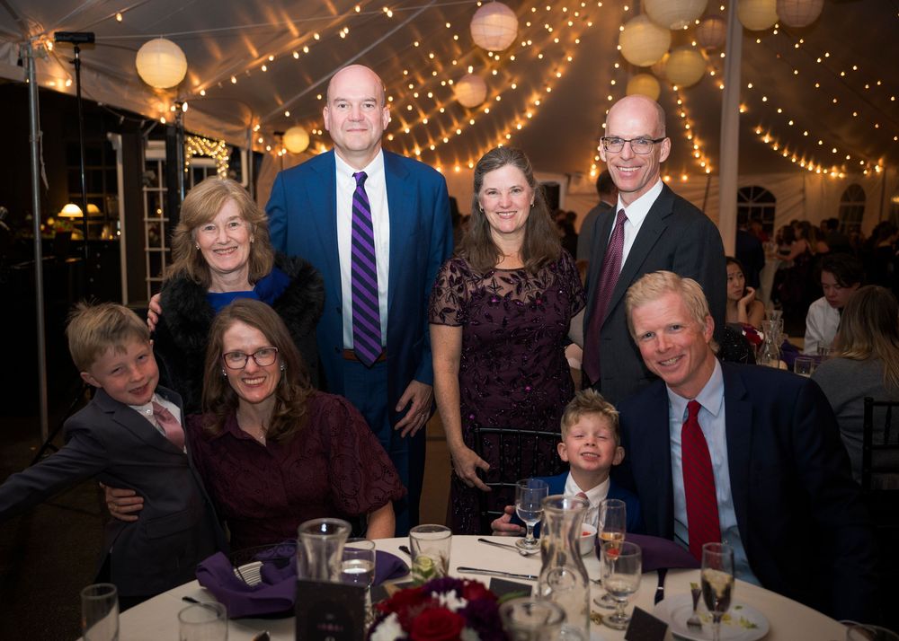 Wedding guests enjoy dinner and conversation at elegantly decorated reception tables under string lights.