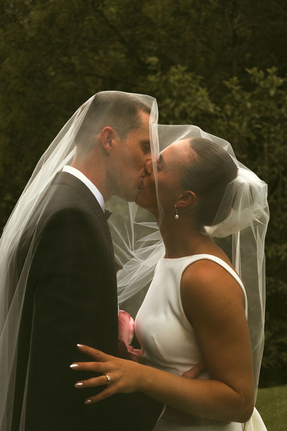 A romantic wedding sequence shows a couple in white sharing intimate kisses under a flowing veil outdoors.