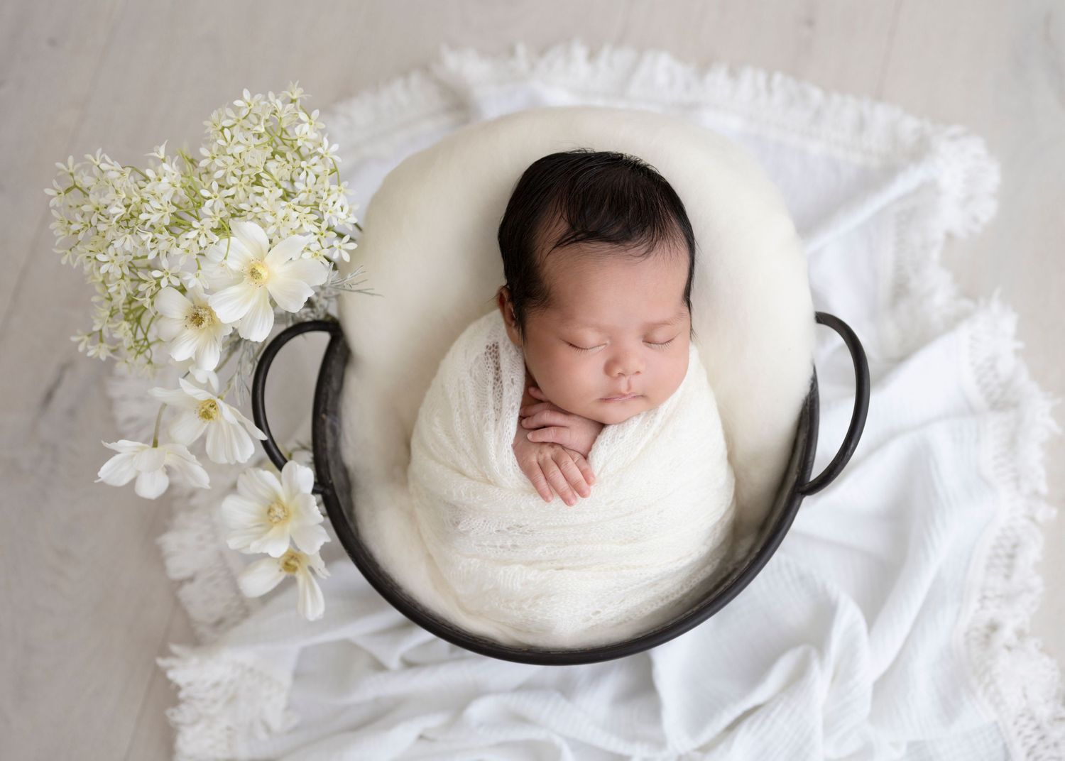 Professional newborn photography studio with framed baby portraits displayed on white walls and minimalist decor.
