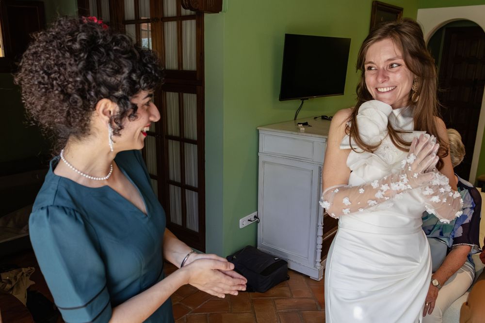 Wedding preparation scene showing people embracing in a green-walled room.
