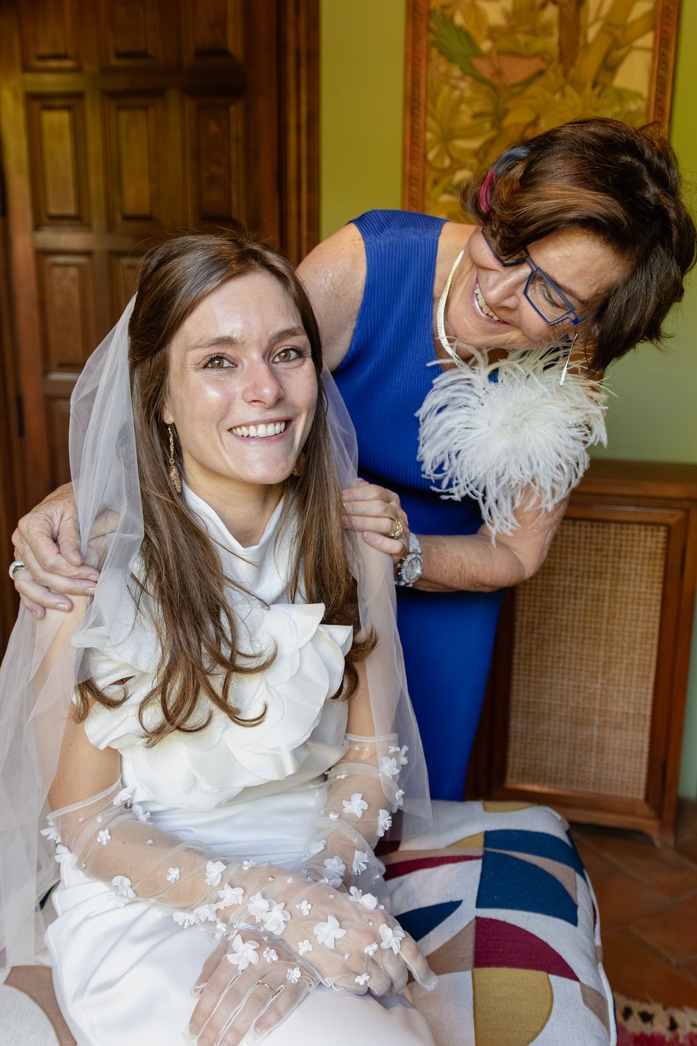 Joyful wedding scene with white bridal gown and veil in an elegant green room.