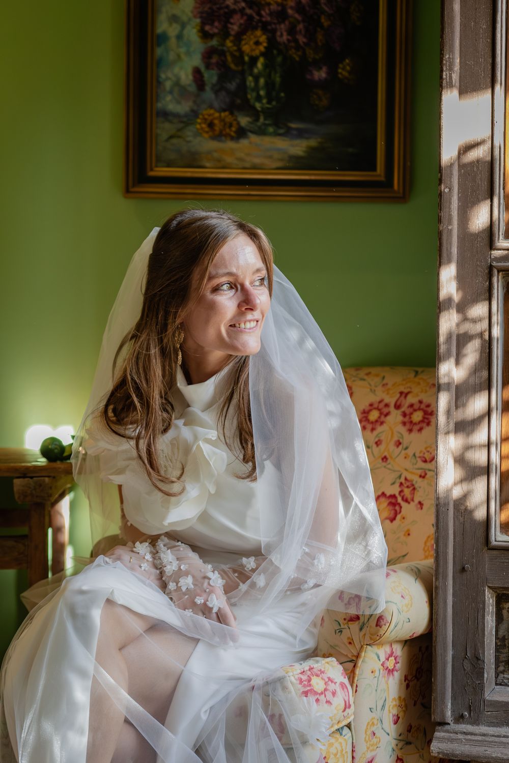 Artistic series capturing ethereal bridal portraits on a floral couch in a room with sage green walls.