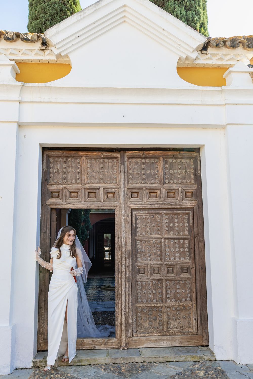 Sequential shots of a bride in white moving along ornate wooden doors of a classic white building exterior.