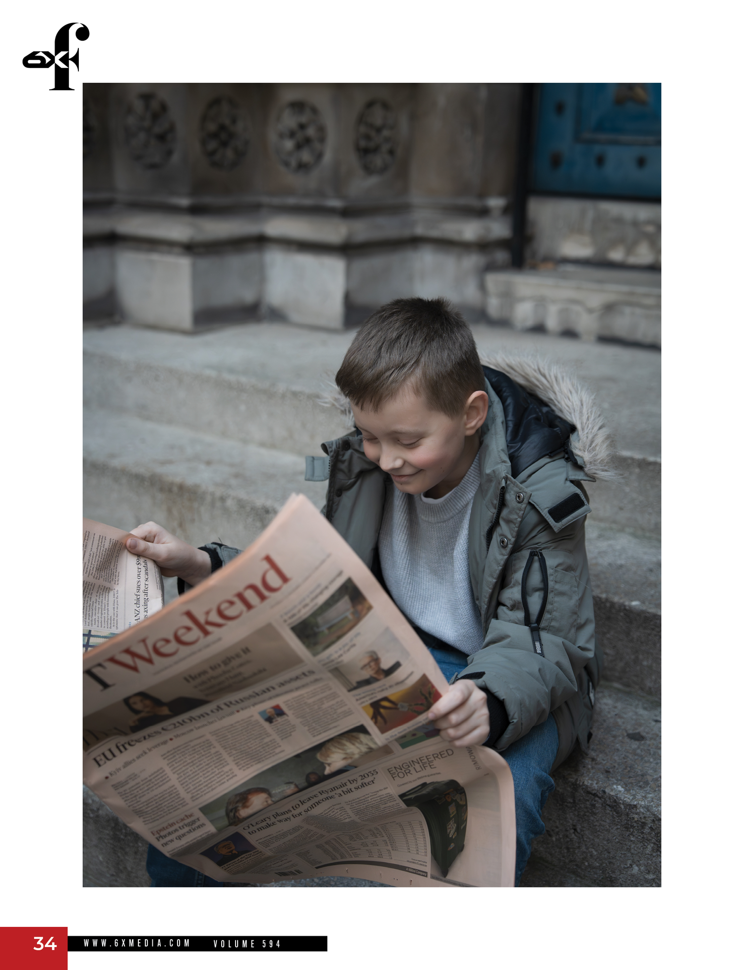 A person in a gray jacket reads a newspaper while sitting on stone steps outdoors.
