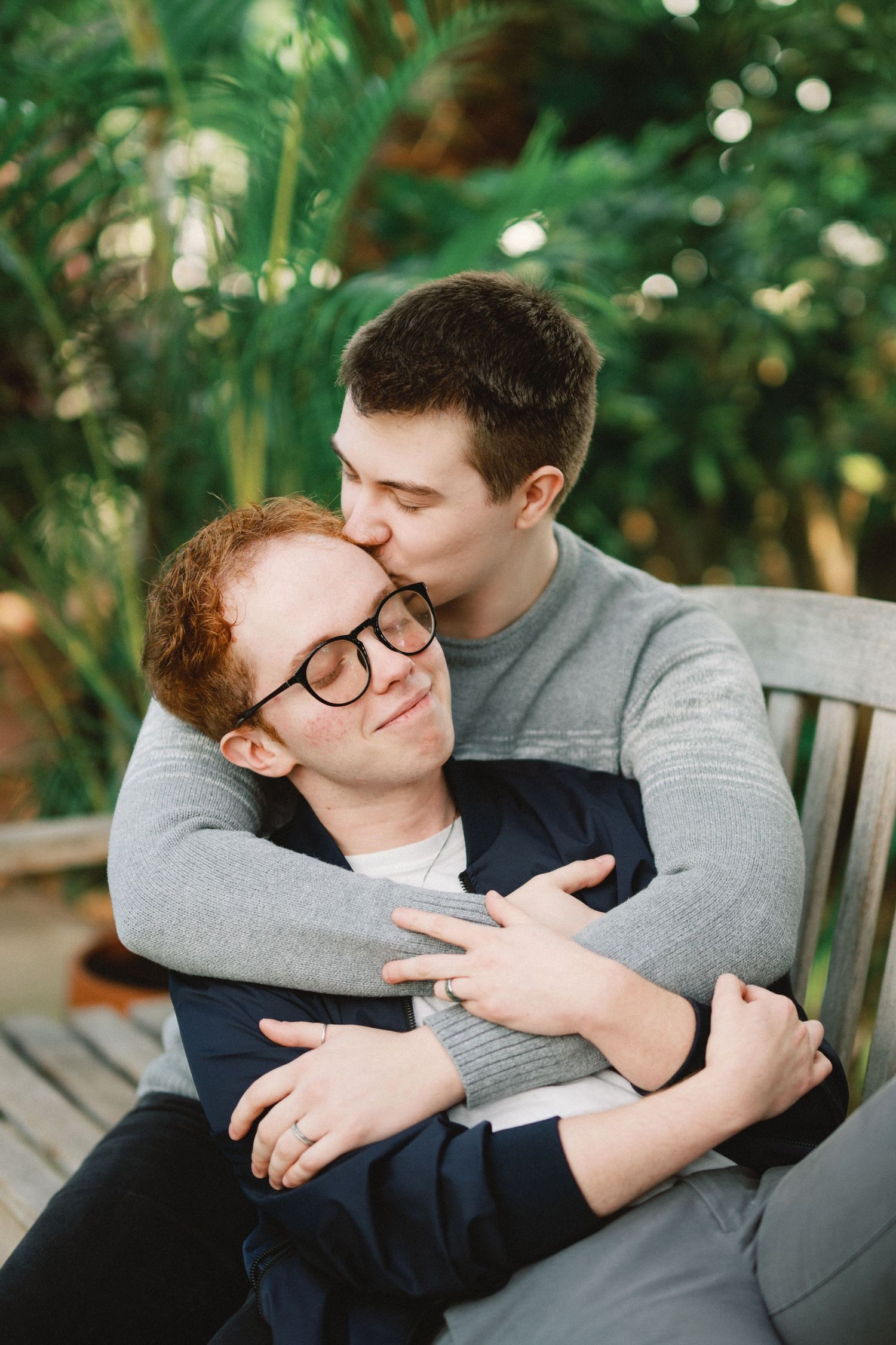 Intimate couple sharing tender moment while sitting on garden bench.