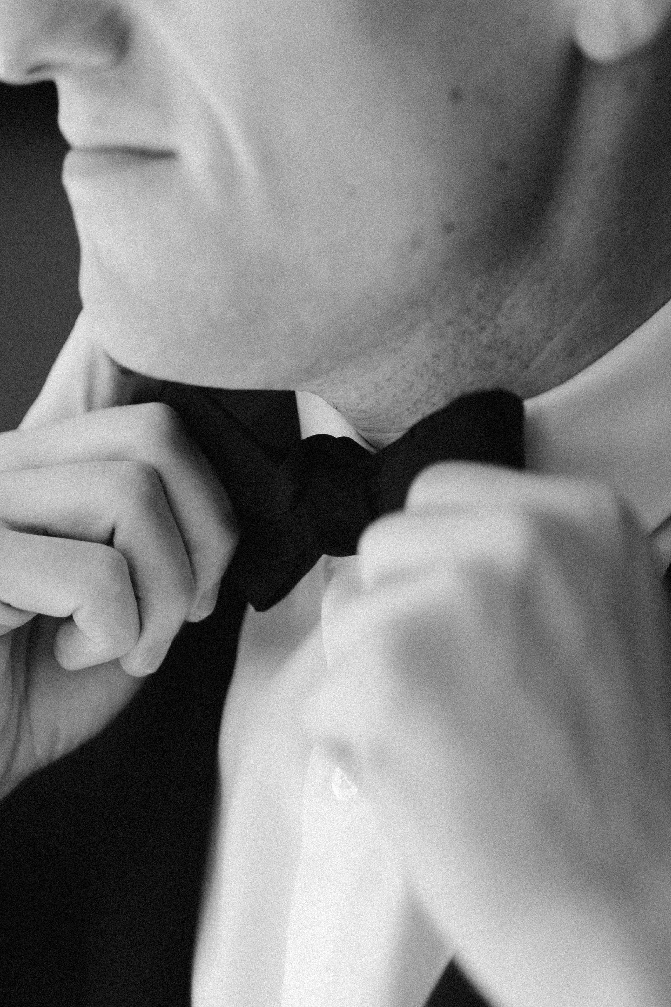 Close-up black and white sequence showing hands adjusting a bow tie.