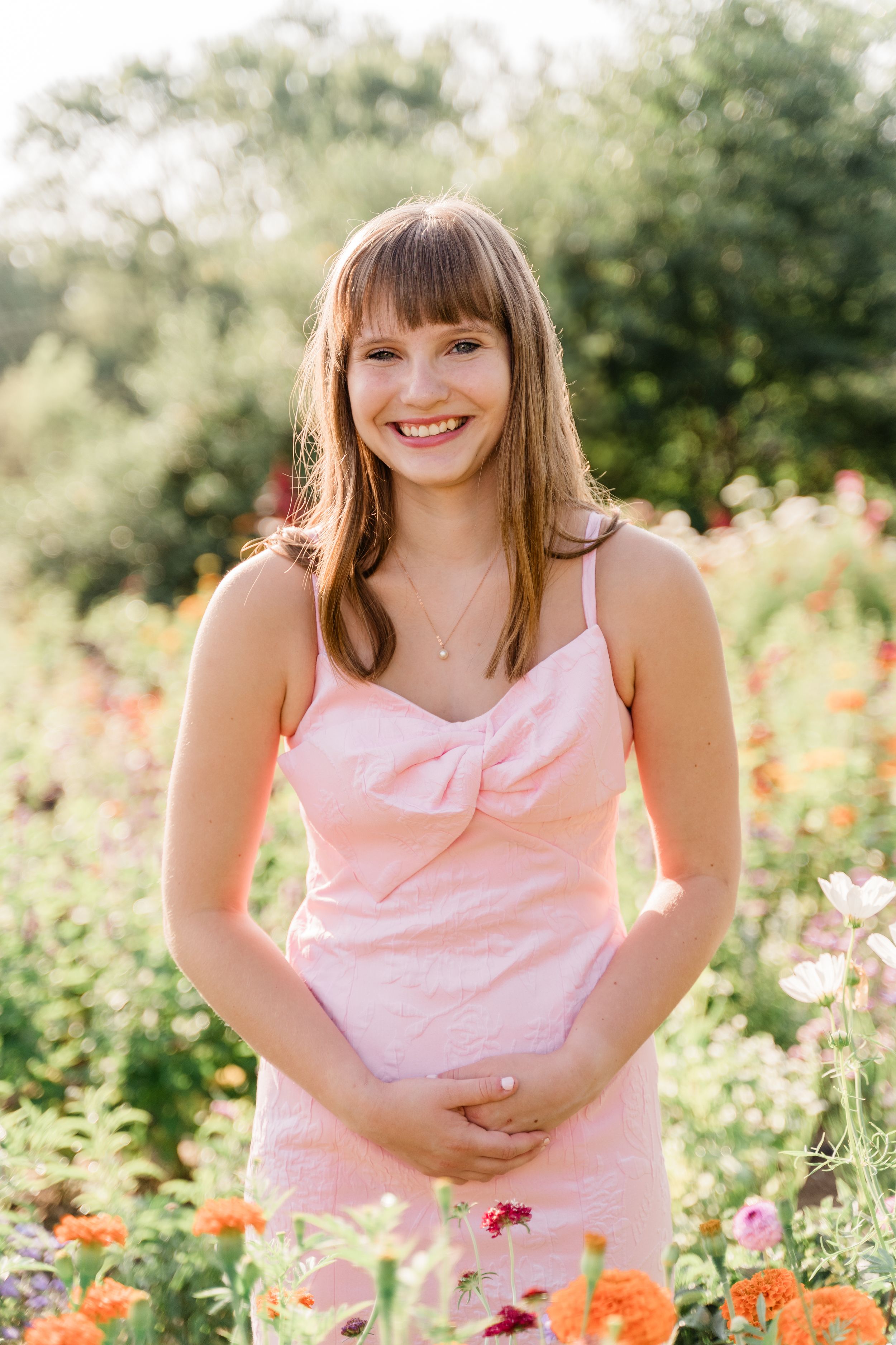 A cheerful summer photoshoot in a garden with blooming orange and pink flowers and soft natural lighting.