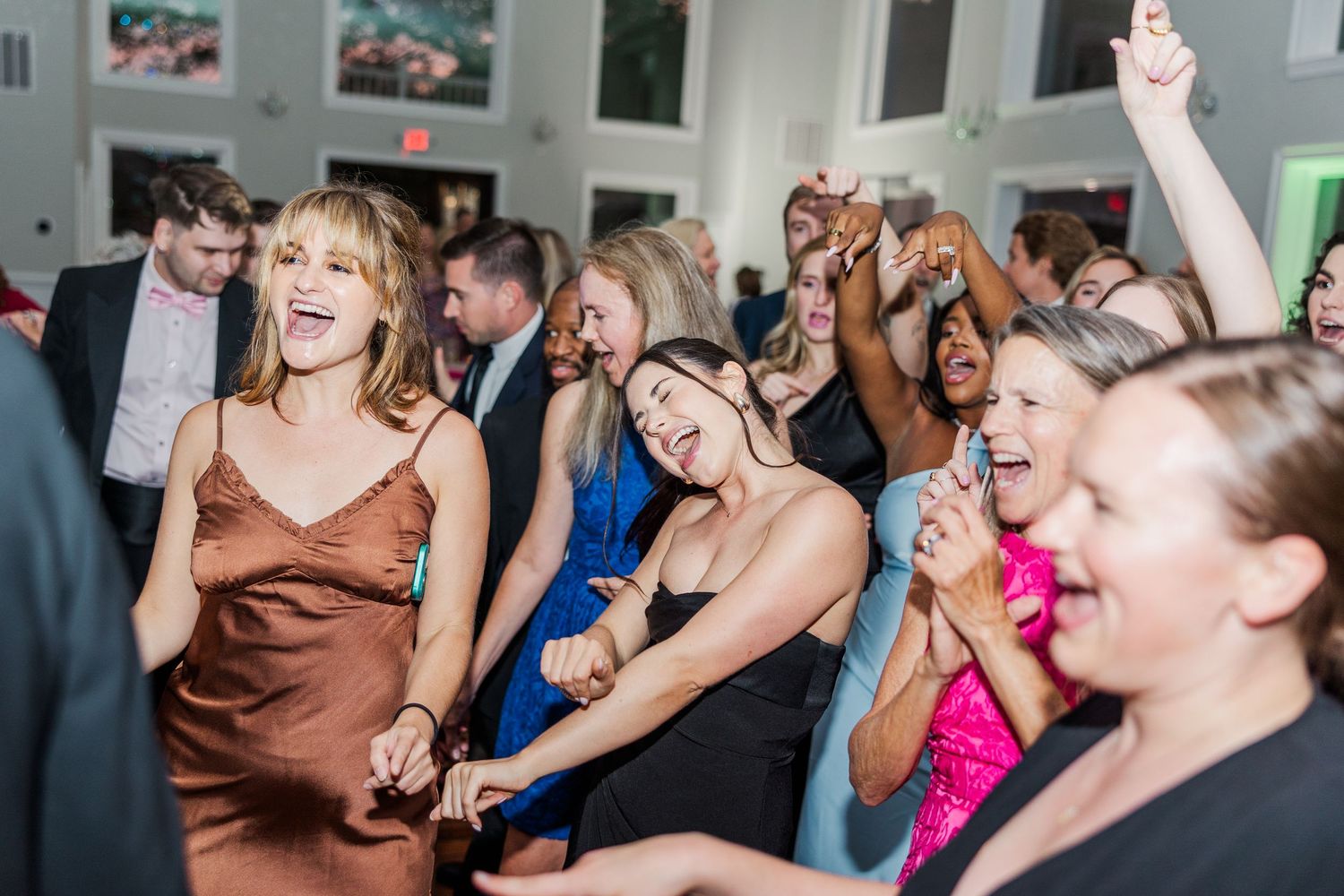 Wedding guests laugh and dance enthusiastically during a lively reception party.