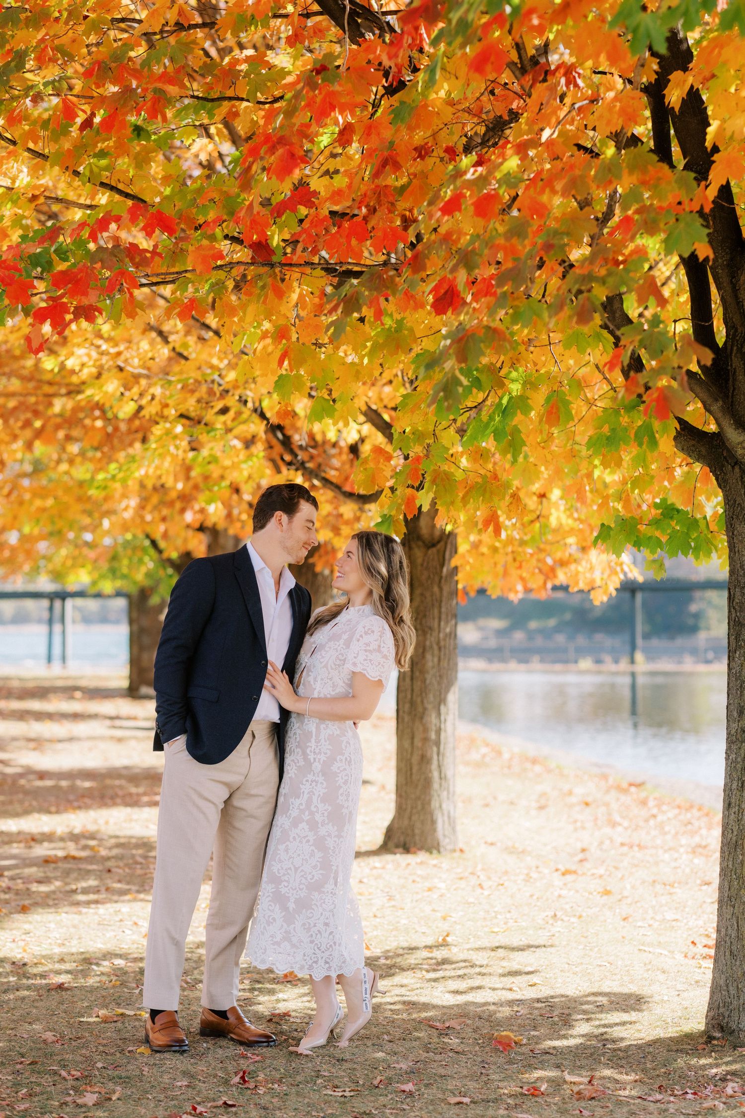 A romantic moment under vibrant autumn trees with golden and red leaves.