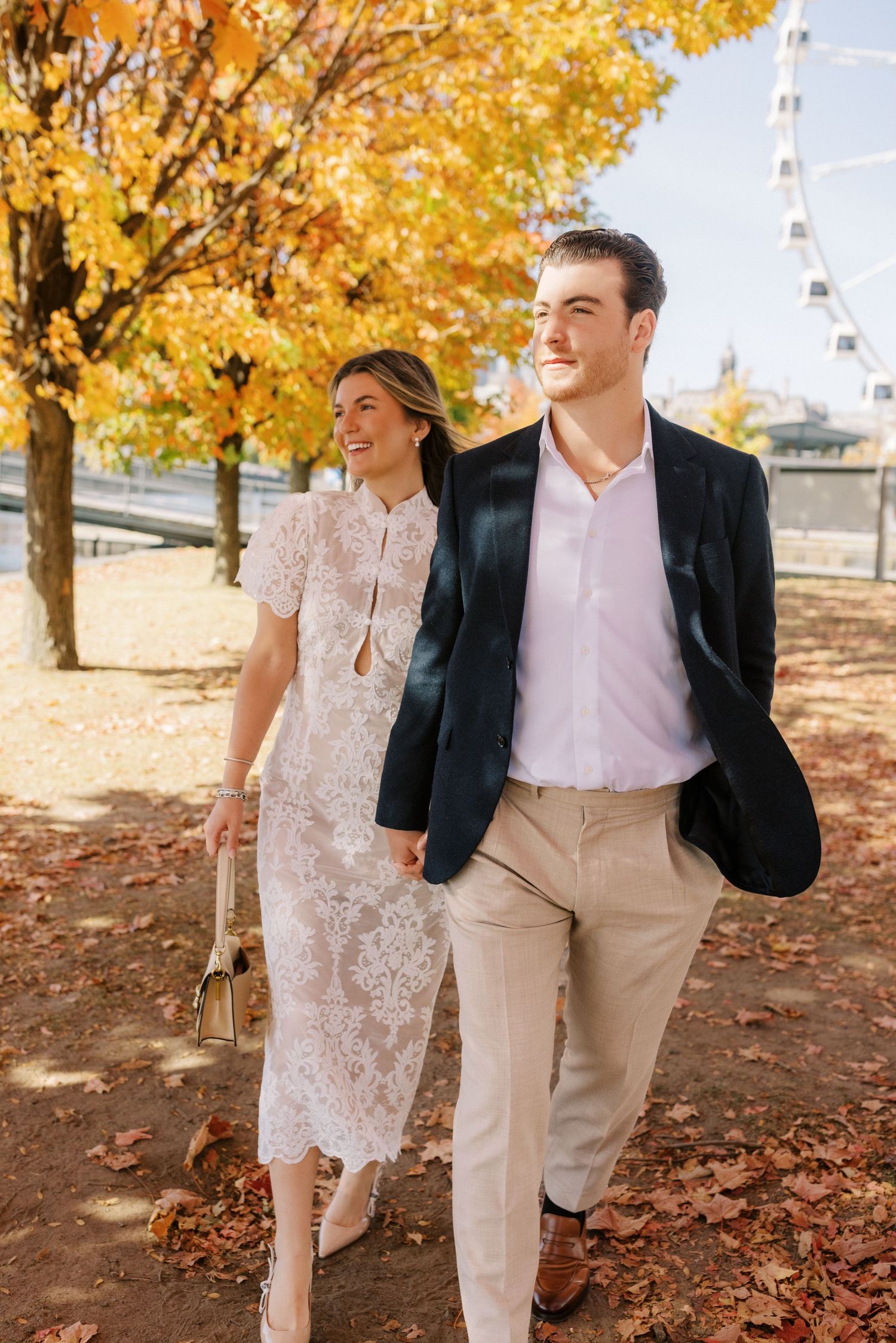 A couple shares a romantic moment while walking through fallen autumn leaves in matching casual attire.