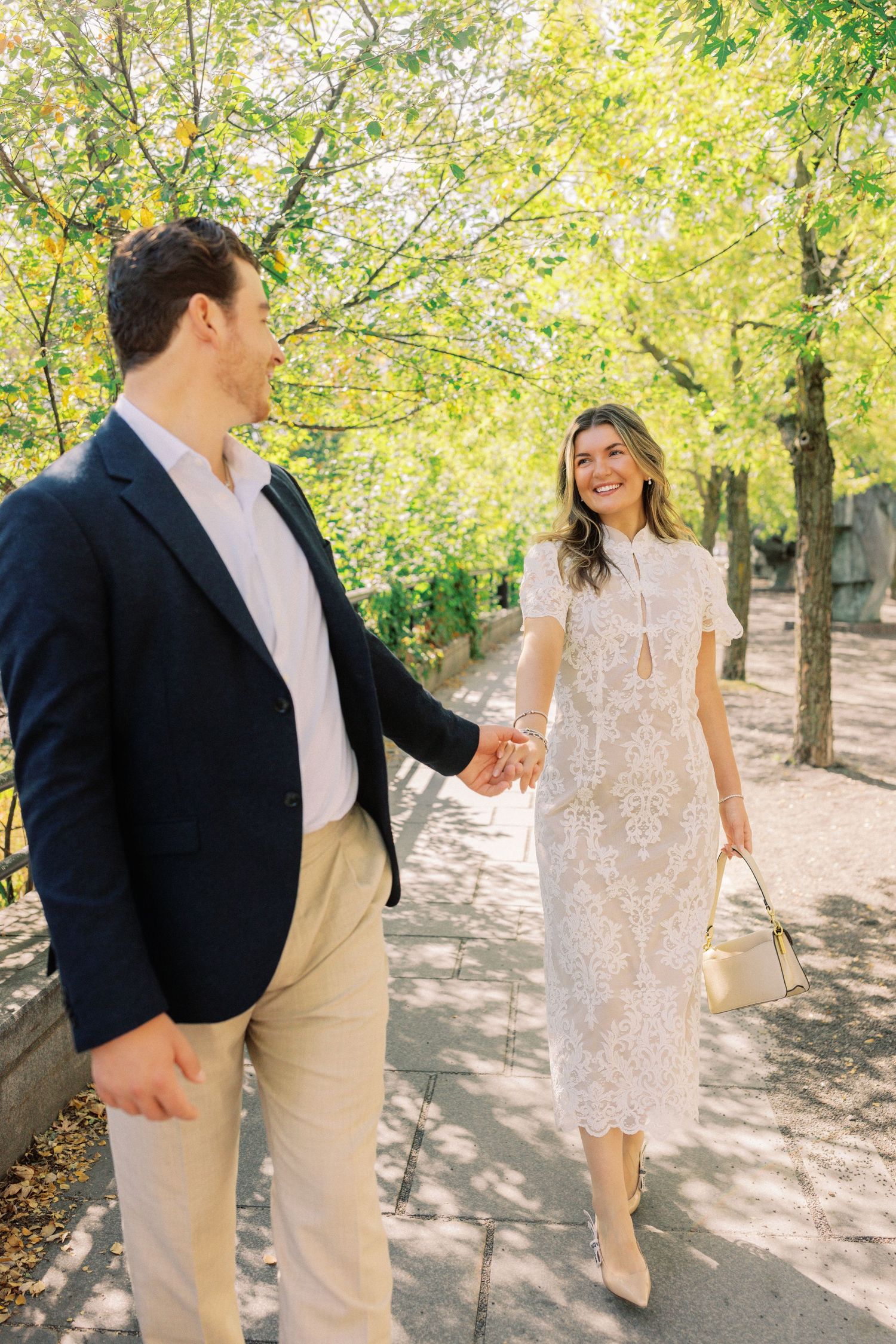 Couple walking together through a sunlit garden path with autumn trees and dappled light.