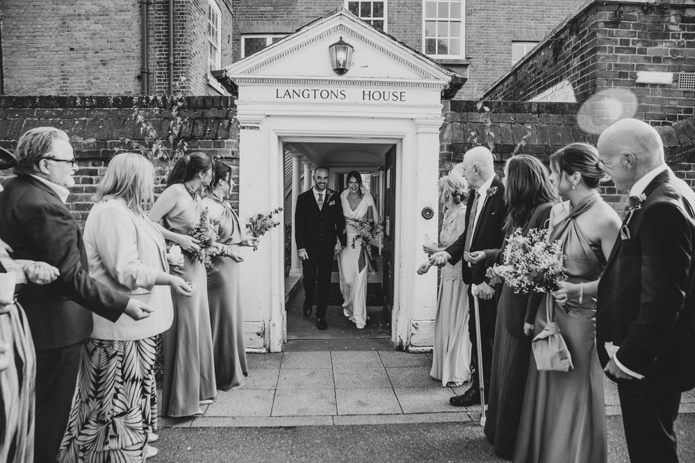 Black and white wedding photos showing guests and wedding party gathered outside a venue entrance.