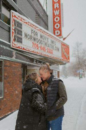 A tender moment shared between two people outside the Norwood Theatre in winter.