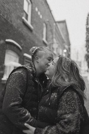 A black and white photo of two people sharing an intimate moment in the snow.
