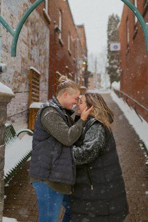 A tender moment shared between two people in winter coats during a snowfall.