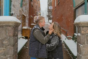 An intimate moment captured between two people in puffy jackets during winter.
