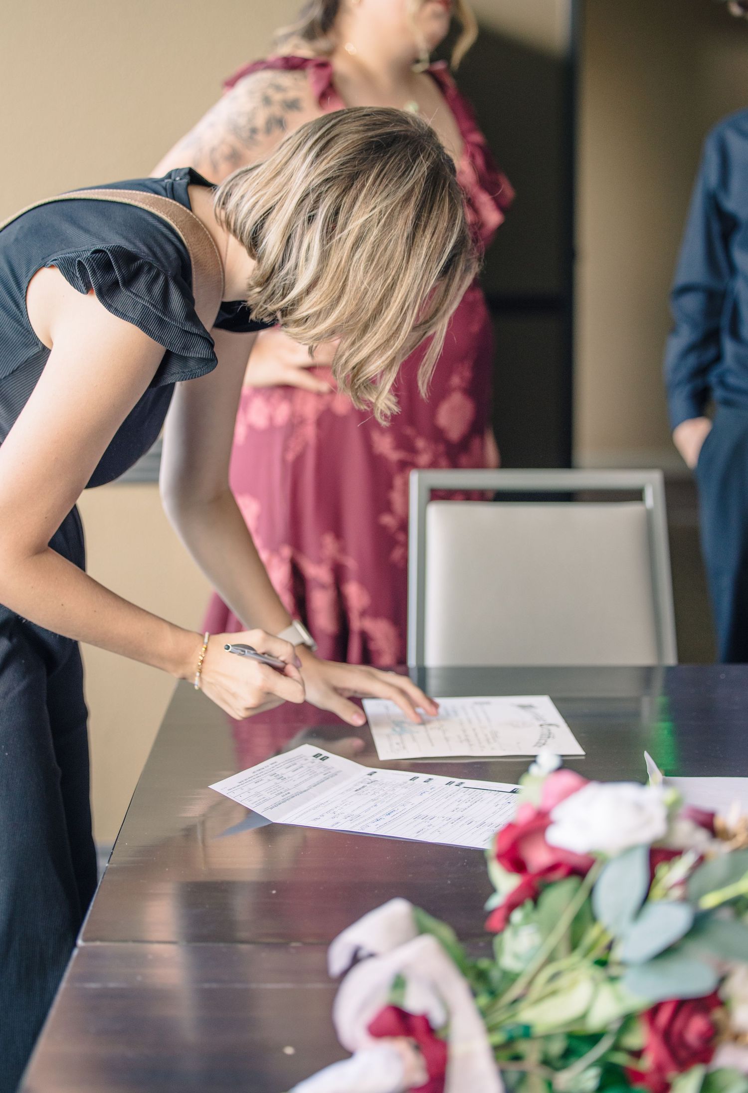 Person leaning over table reviewing documents with flowers and decor visible.