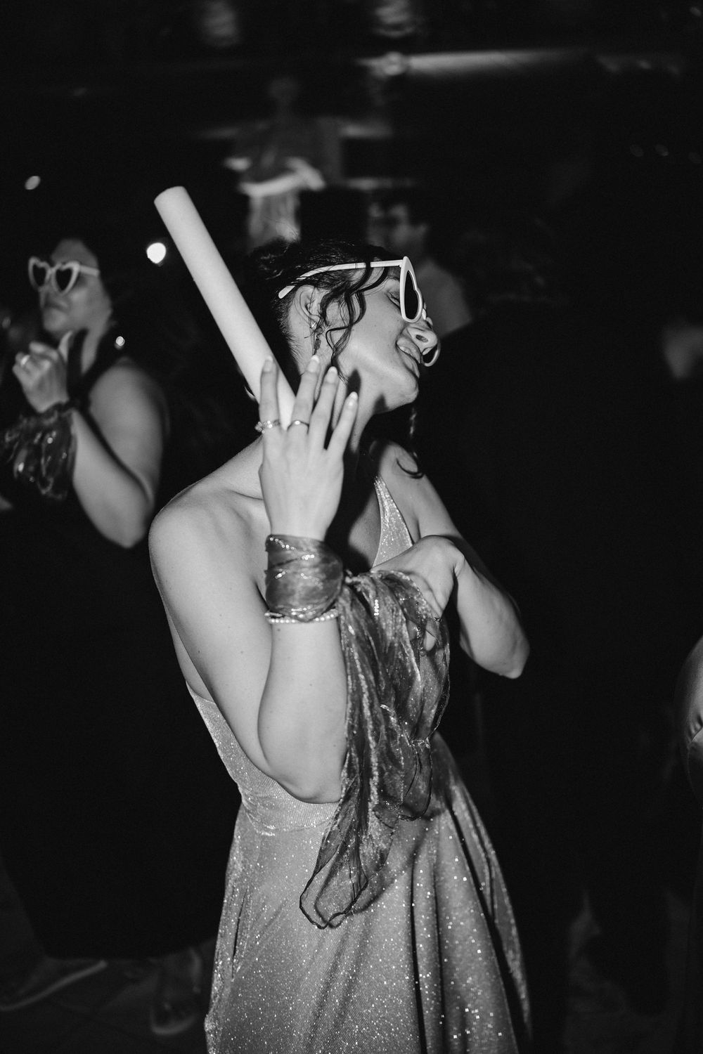Black and white photos of people dancing and enjoying themselves at a party with sparkly dresses and raised hands.