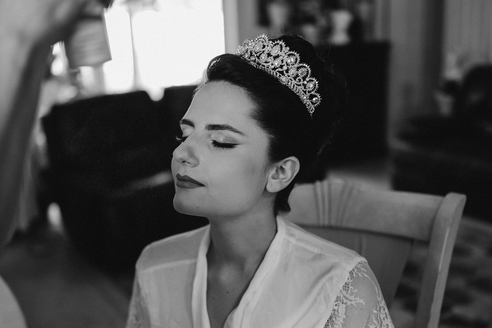 A bride wearing a tiara and robe is getting her makeup done in a black and white photo collage.
