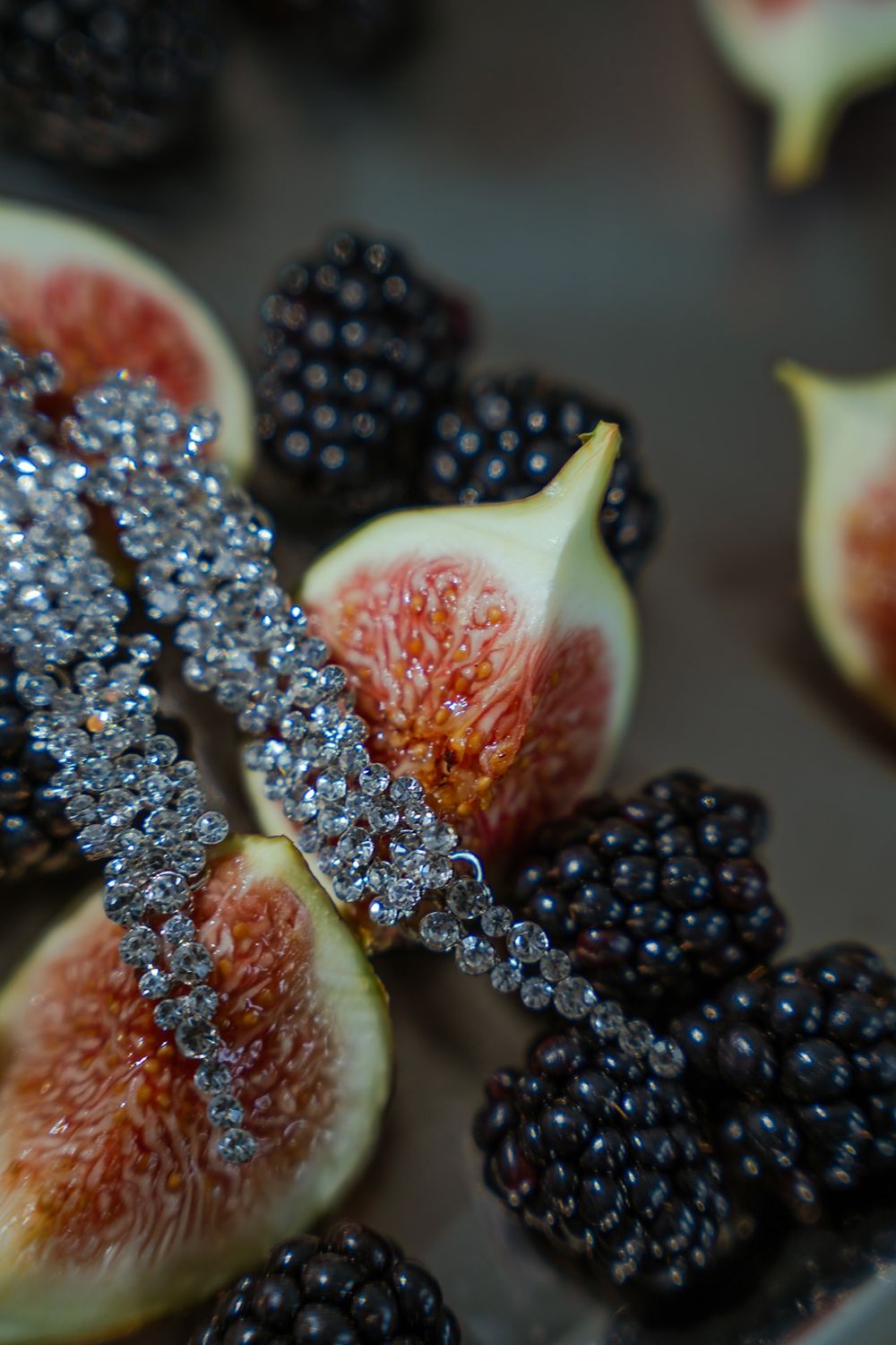 Close-up of fresh figs and blackberries with sparkling crystal details.