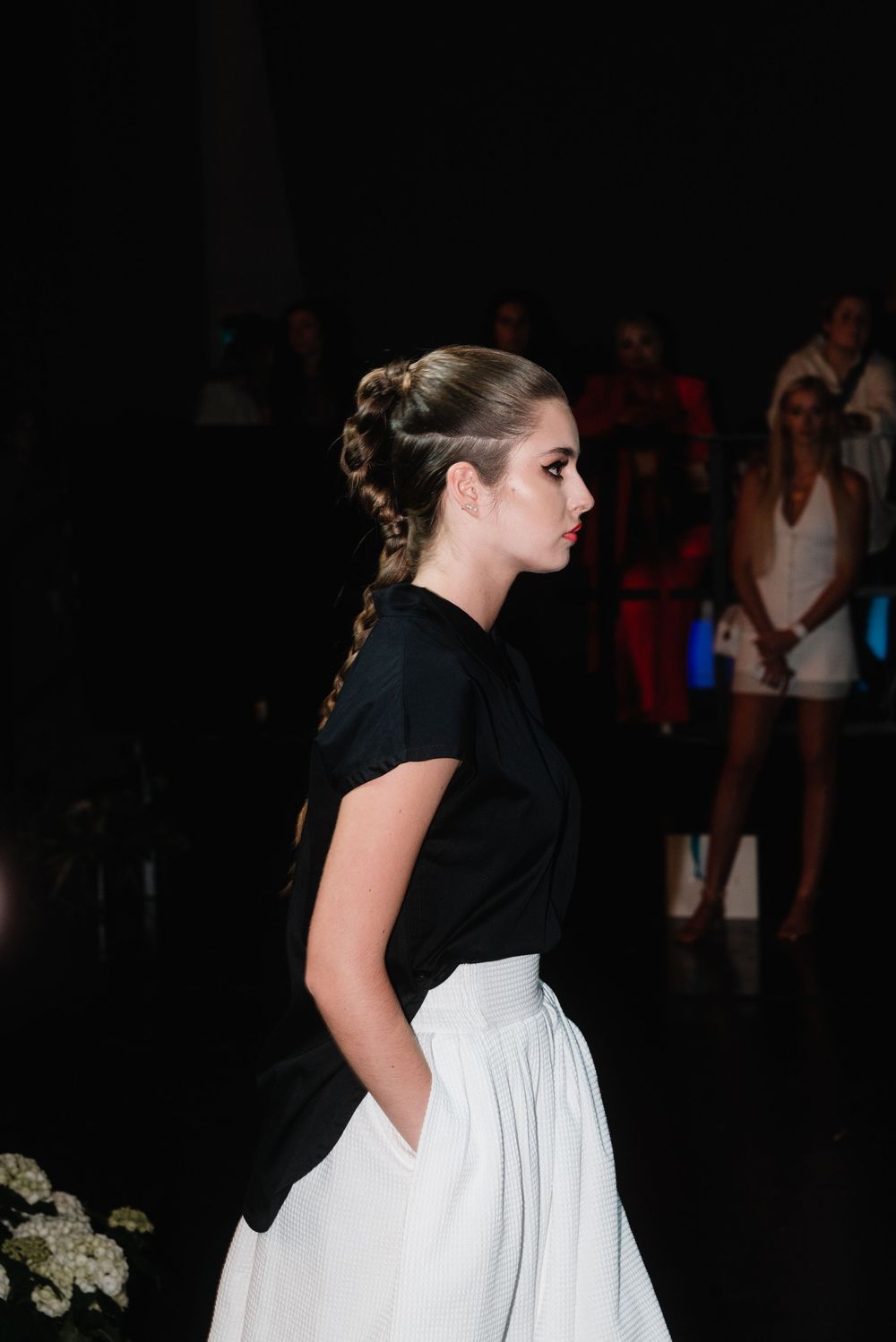 Black and white dress on display at fashion show with dark backdrop.