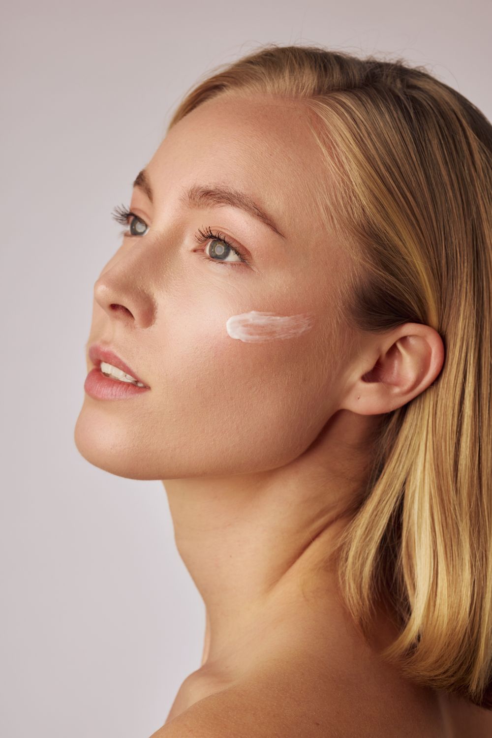 Beauty portrait with dewy skin and minimalist makeup against neutral background.