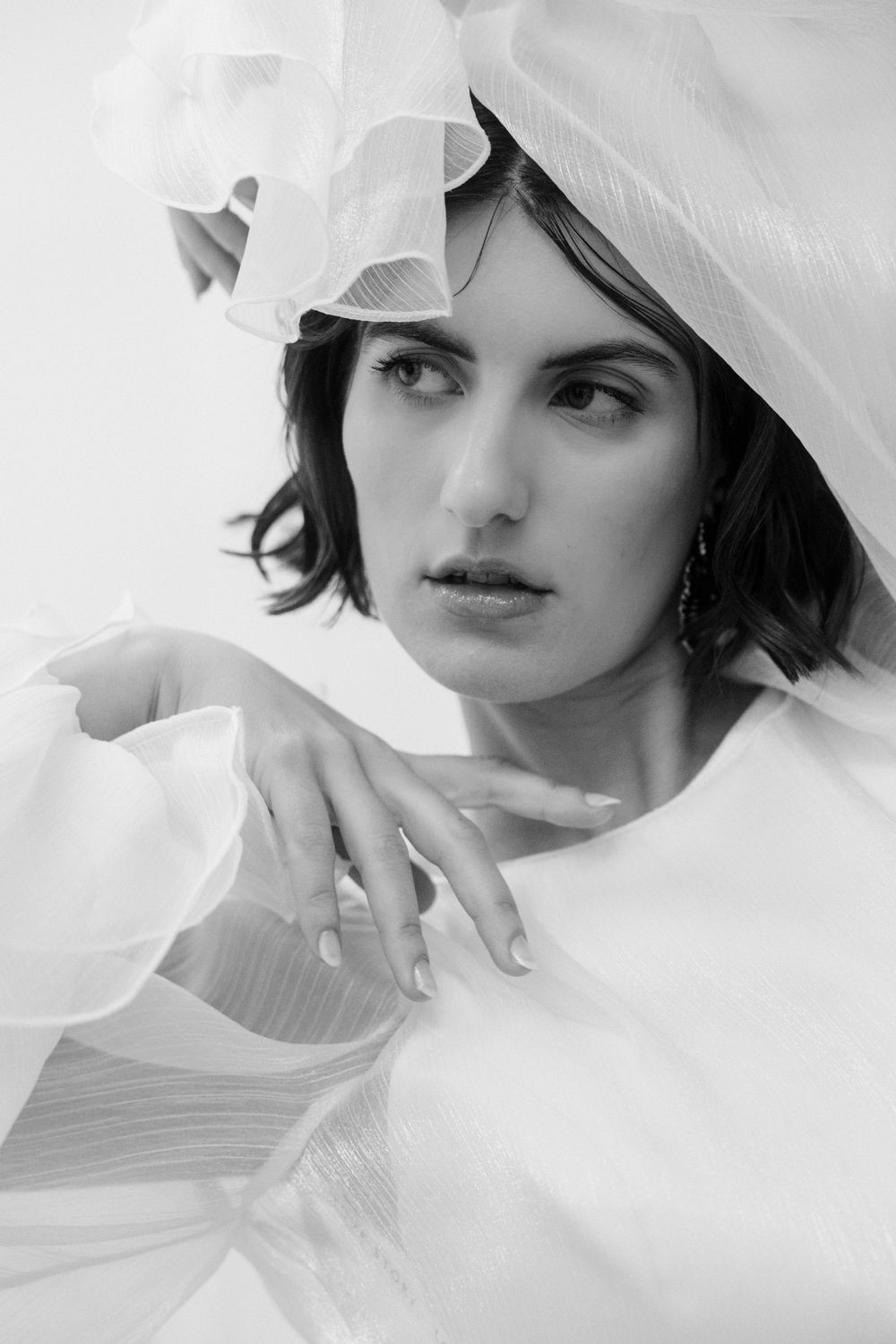 Artistic portrait with flowing white fabric and dramatic lighting.