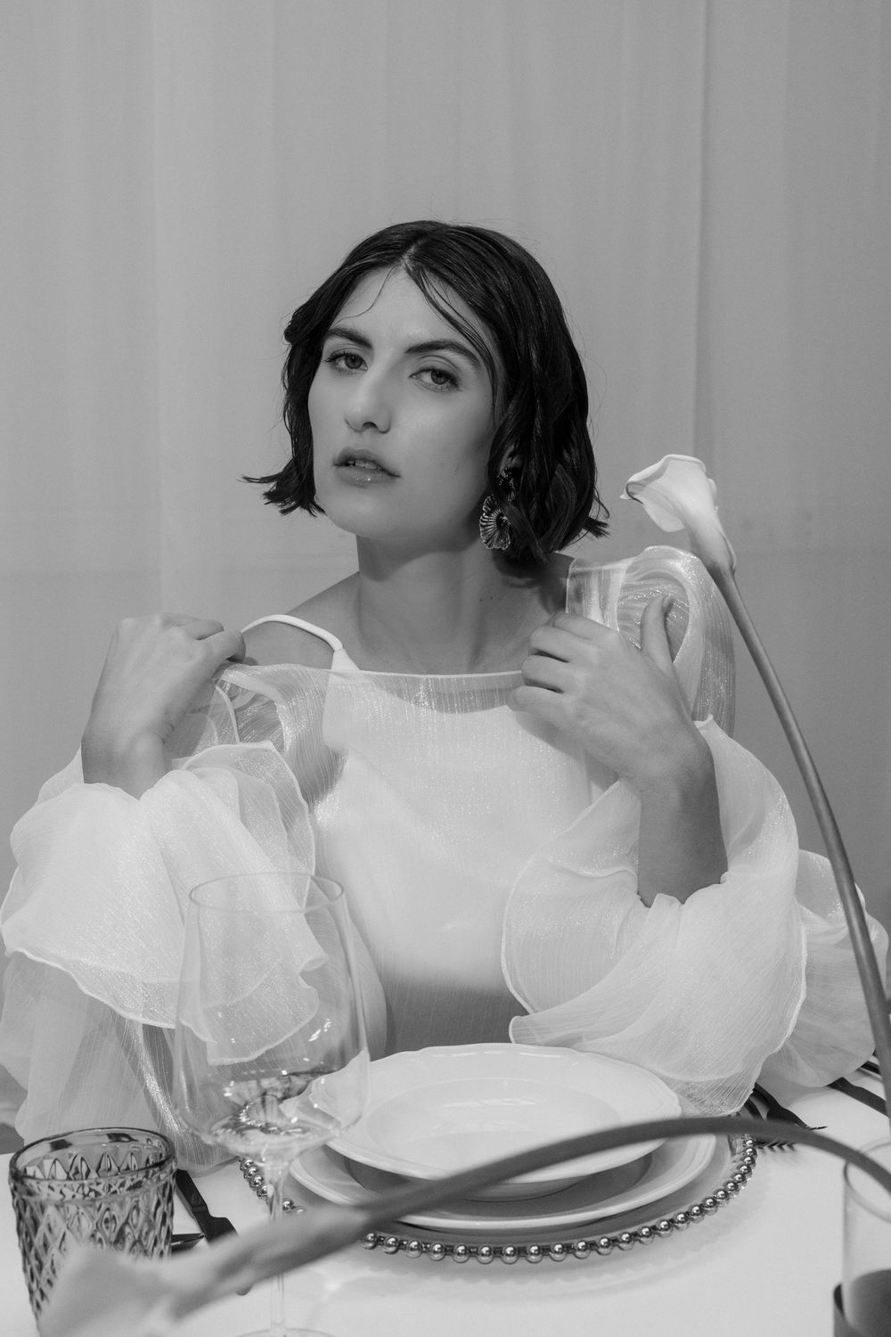 Fashion photo featuring white ruffled dress against minimalist grey backdrop.