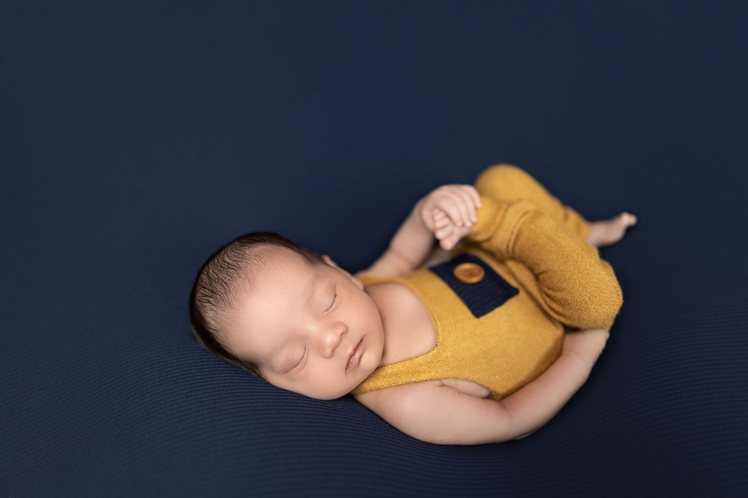A series of progressive images showing a baby sleeping in a yellow onesie against a dark background.