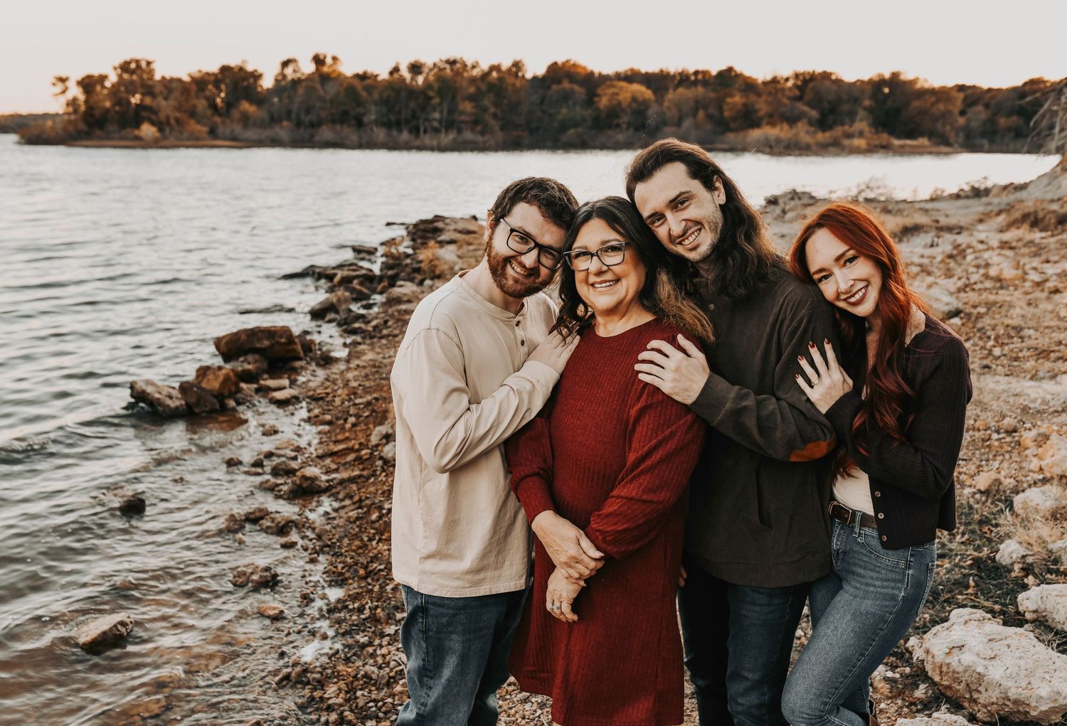 Grandparents with their three adult children in cozy fall outfits during a lakeside session by April Pinto Photography.