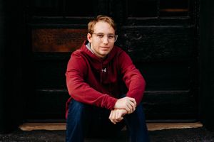 A person in a burgundy sweatshirt poses against a dark background in a series of moody portrait shots.