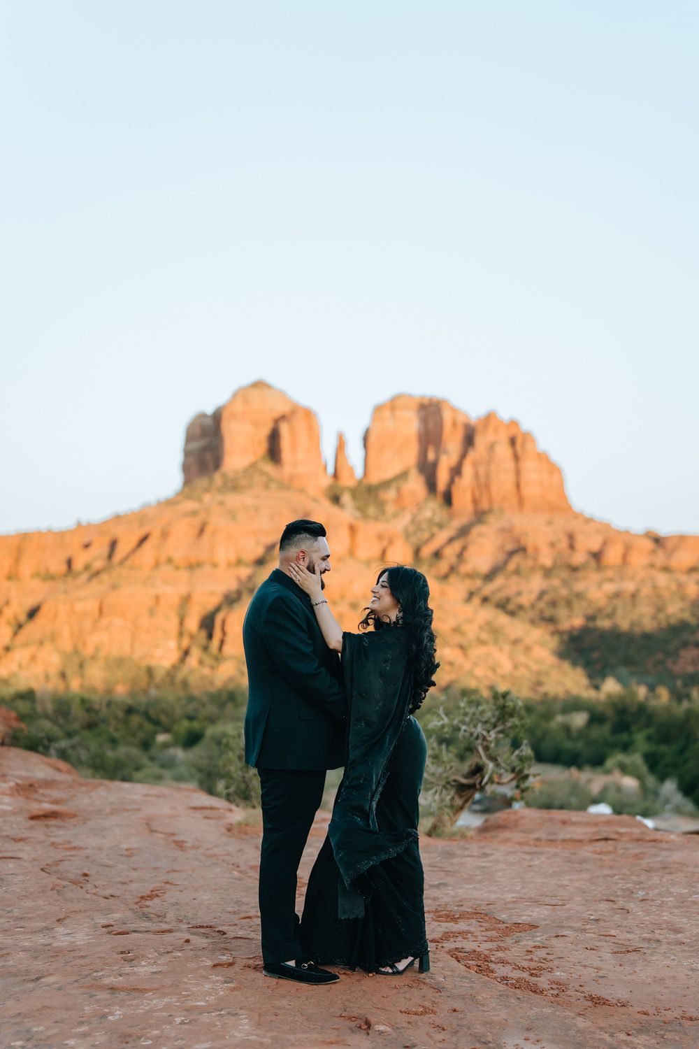 Romantic desert photography session with couple in black against stunning red rock formations.