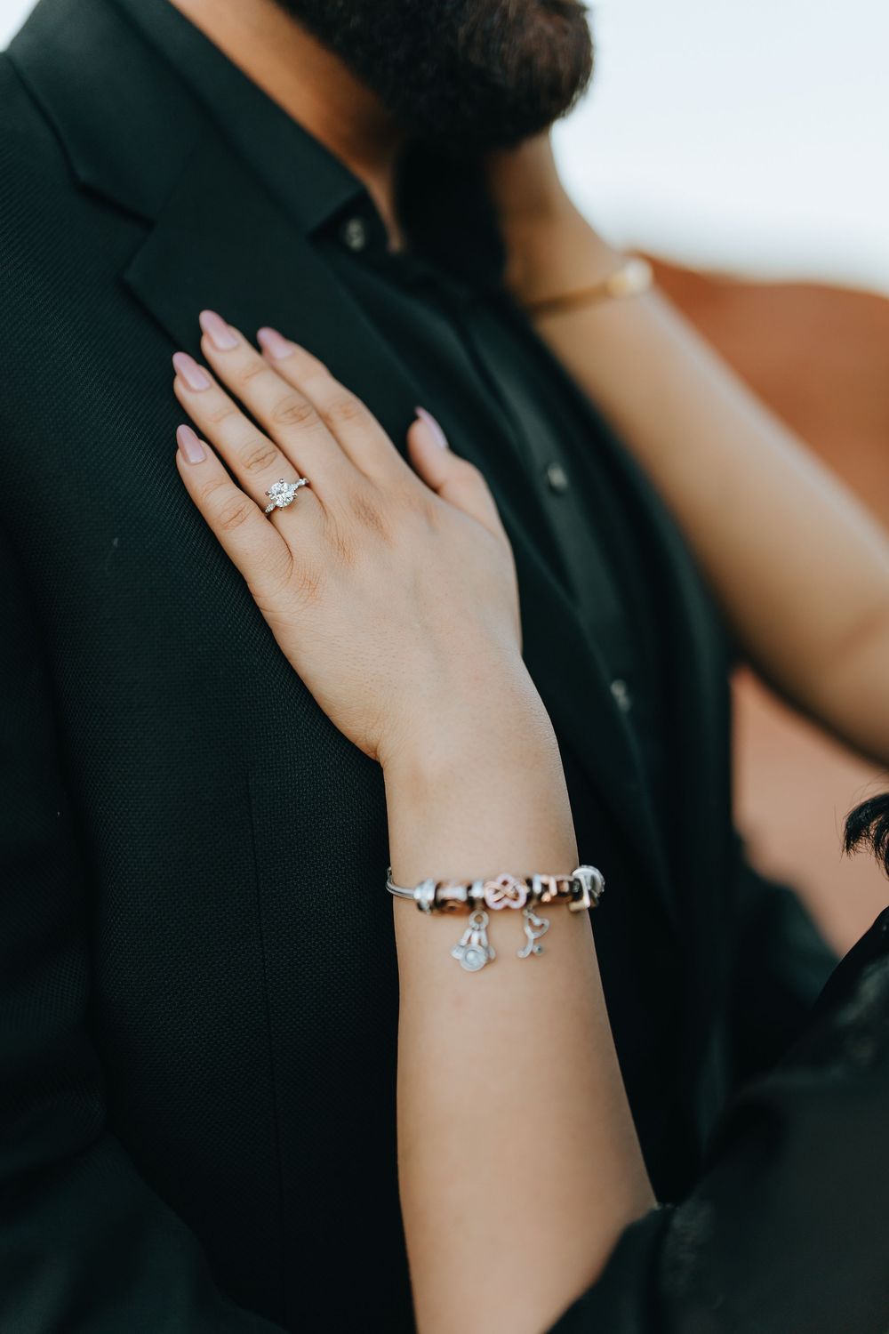 Close-up shots of hands wearing elegant jewelry and rings against a dark background.