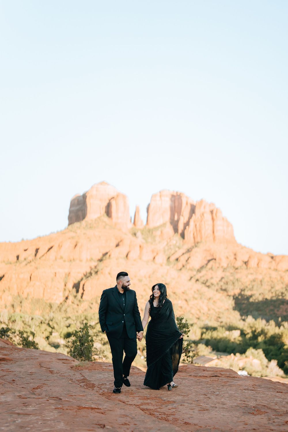 Romantic desert photoshoot with dramatic red rock cliffs in background.