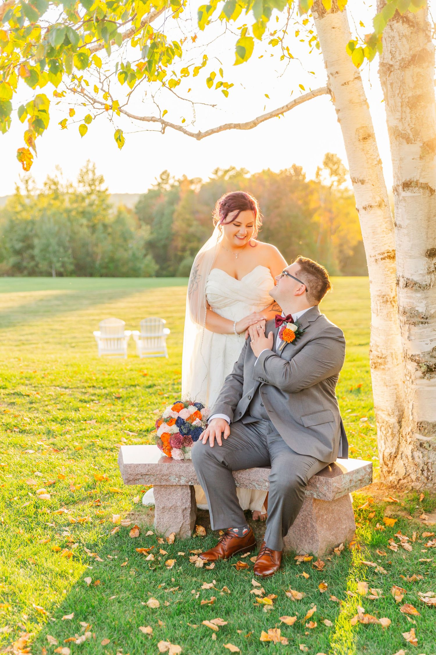 Couple shares romantic moments on stone bench surrounded by autumn trees at sunset in golden light.