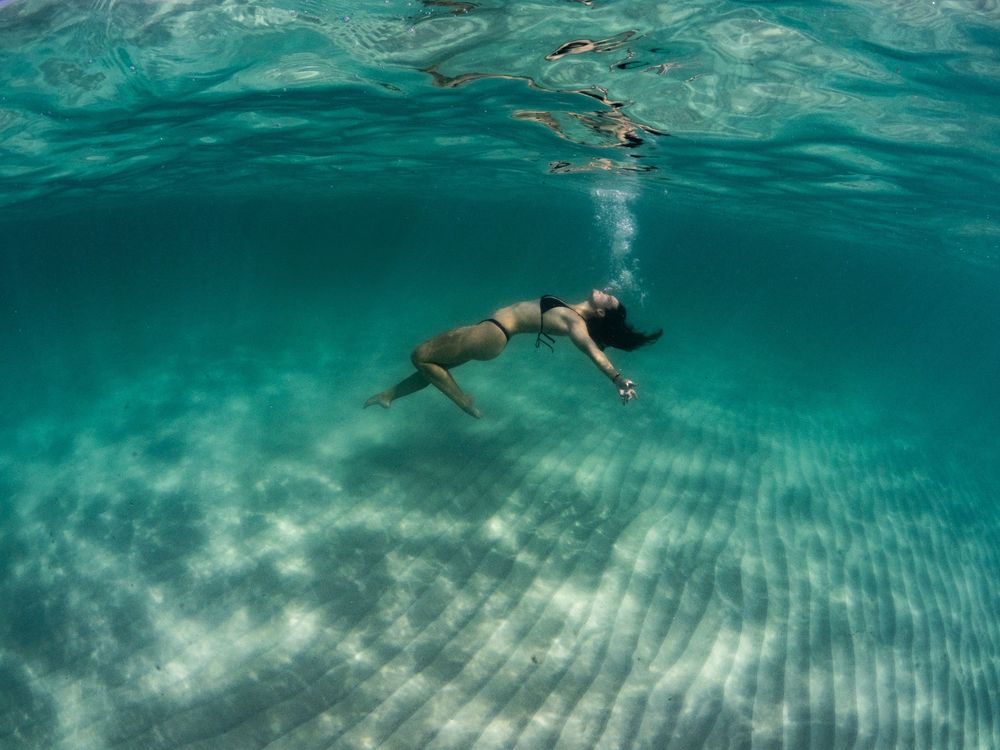 Multiple underwater shots showing swimmers floating in crystal clear turquoise waters with sunlight patterns.