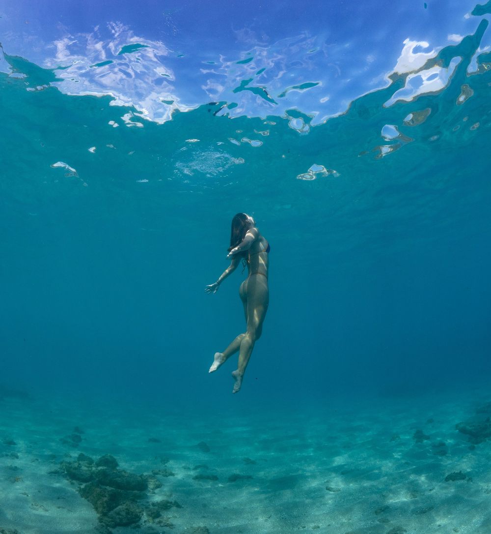 Underwater scene of a swimmer floating weightlessly in crystal clear turquoise waters.