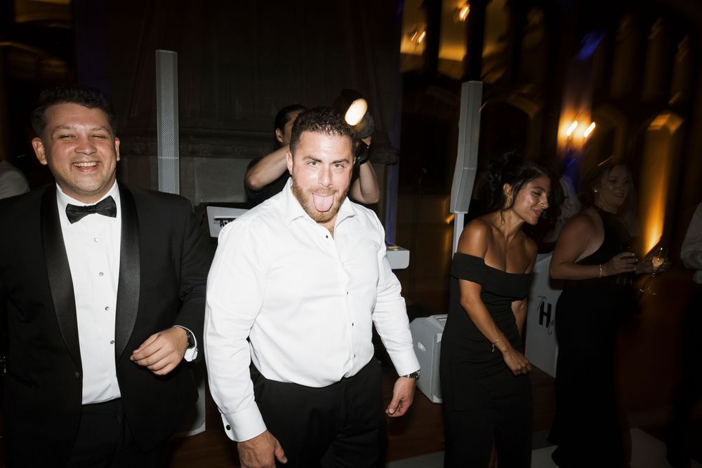 Wedding guests in formal attire dancing and celebrating at an indoor evening reception party.