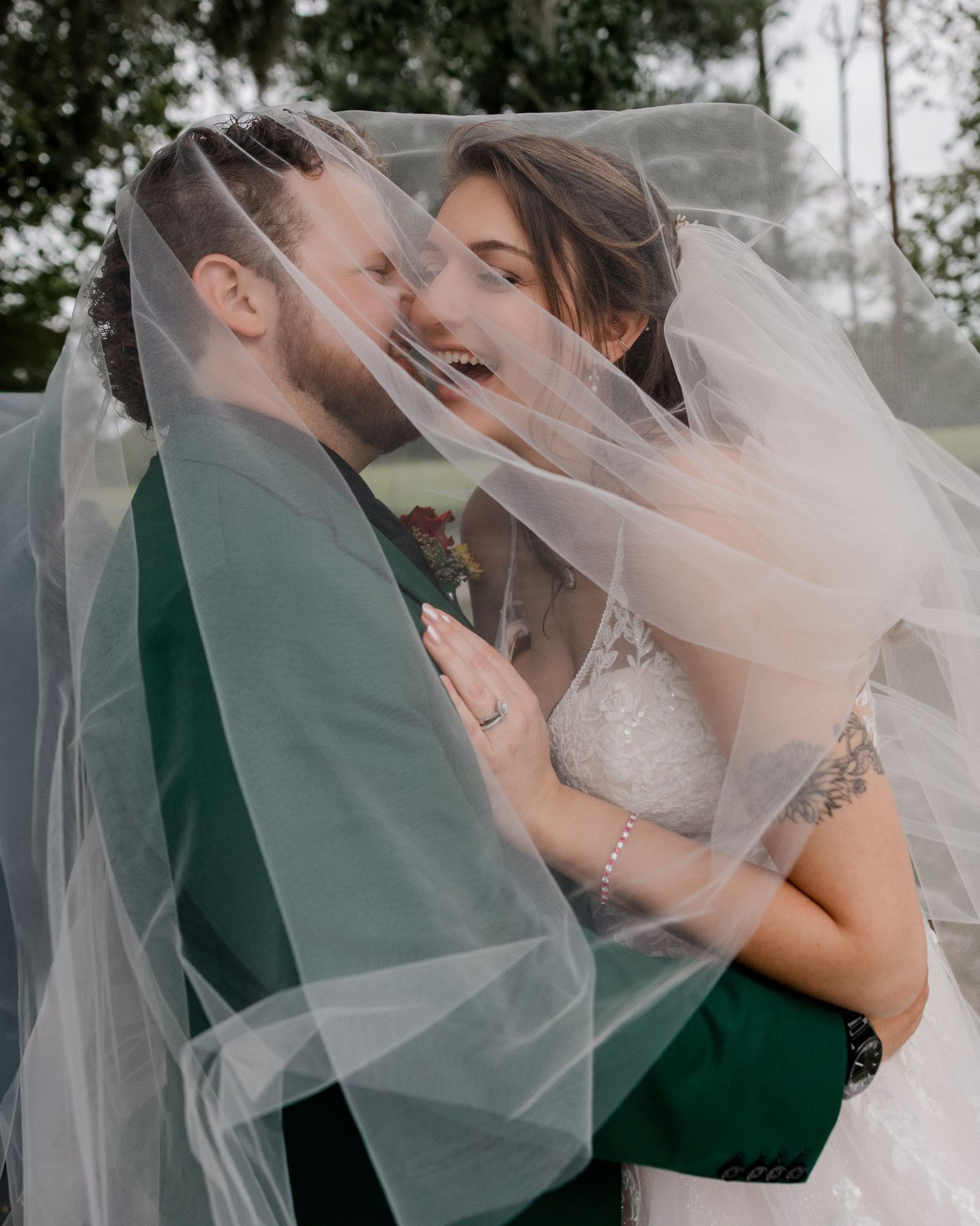 A romantic wedding couple embraces under a flowing veil in a series of intimate poses.