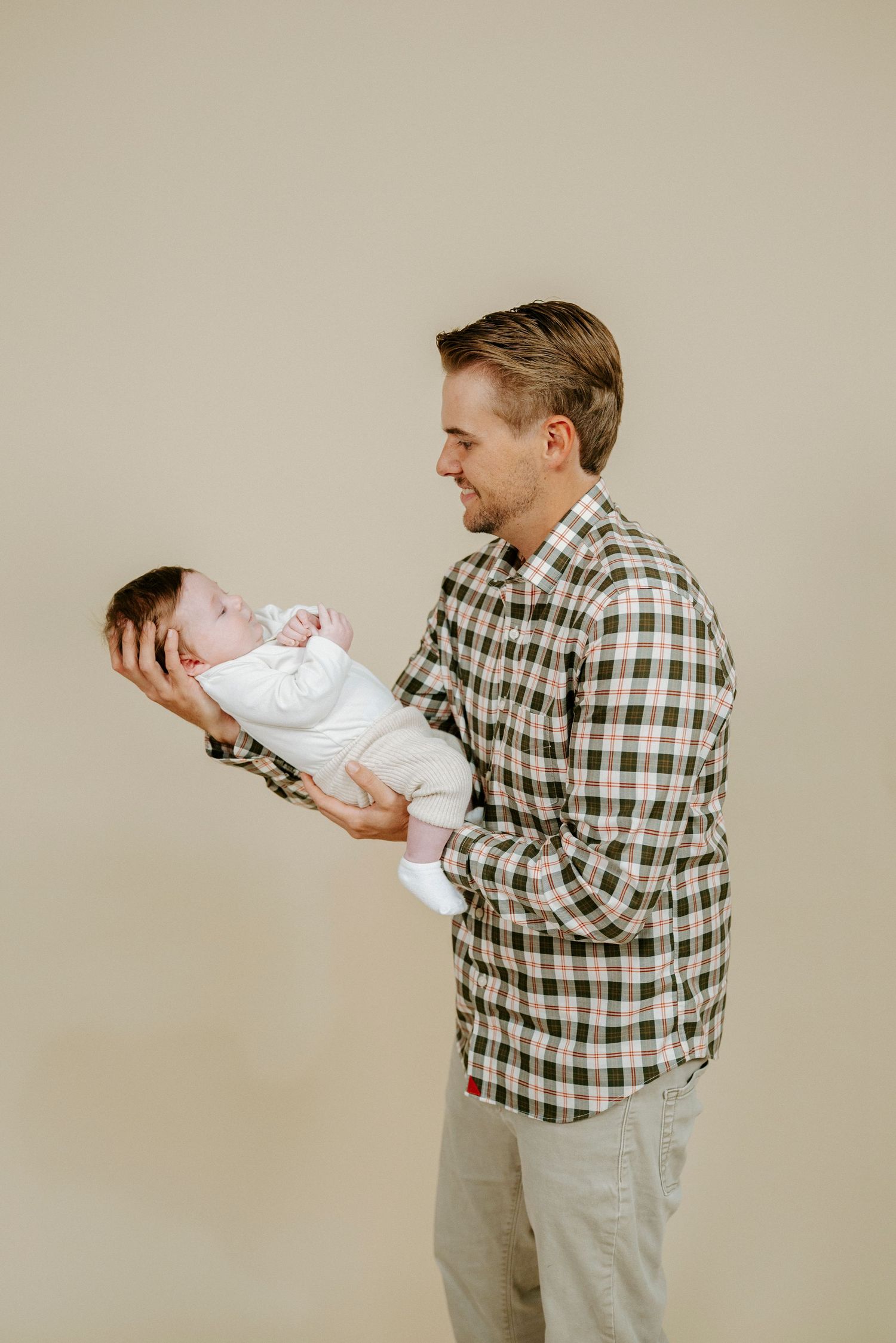 A sequence of photos shows a person in a plaid shirt holding and interacting with a baby wearing white.