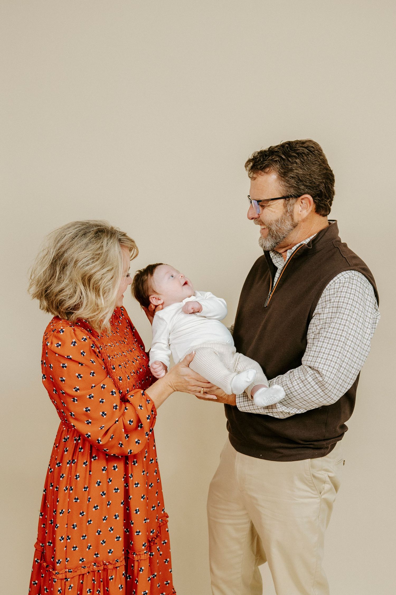 A series of four progressive photos showing a tender family moment with a newborn baby in a studio setting.