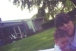 People enjoying a sunny day outdoors on a grassy lawn with trees overhead.