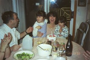 Family dinner gathering around a table with plates of food and drinks.