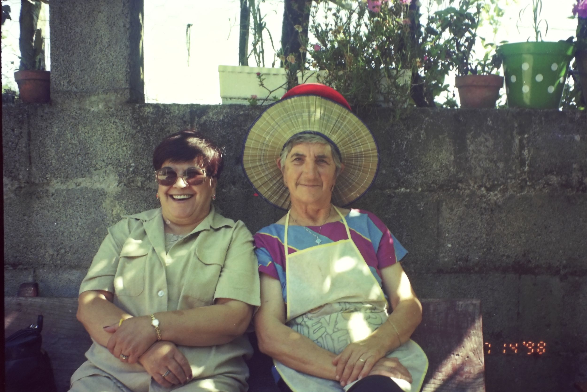 Group relaxing outdoors wearing casual summer clothing and sun hats.