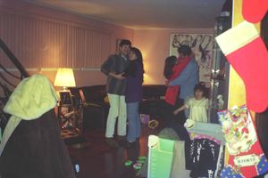 A group gathered in a dimly lit living room surrounded by gifts and decorations.