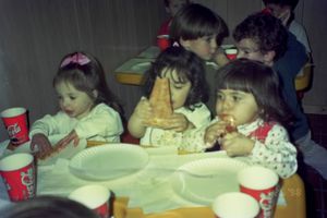 Children sitting at a table with red cups during what appears to be a party.